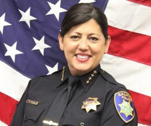 Headshot of Chief Fresé, smiling, American flag backdrop